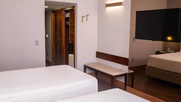 Habitación de hotel con dos camas, un banco, un televisor y un armario.