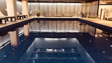 Una piscina techada, sillones reclinables de piscina