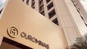 Un grand immeuble avec une enseigne indiquant « OUROMINAS » à sa base.