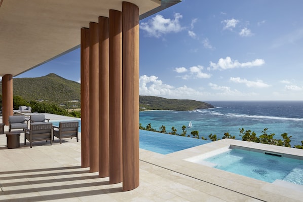 Zona junto a la piscina con vistas al océano y a un paisaje montañoso.