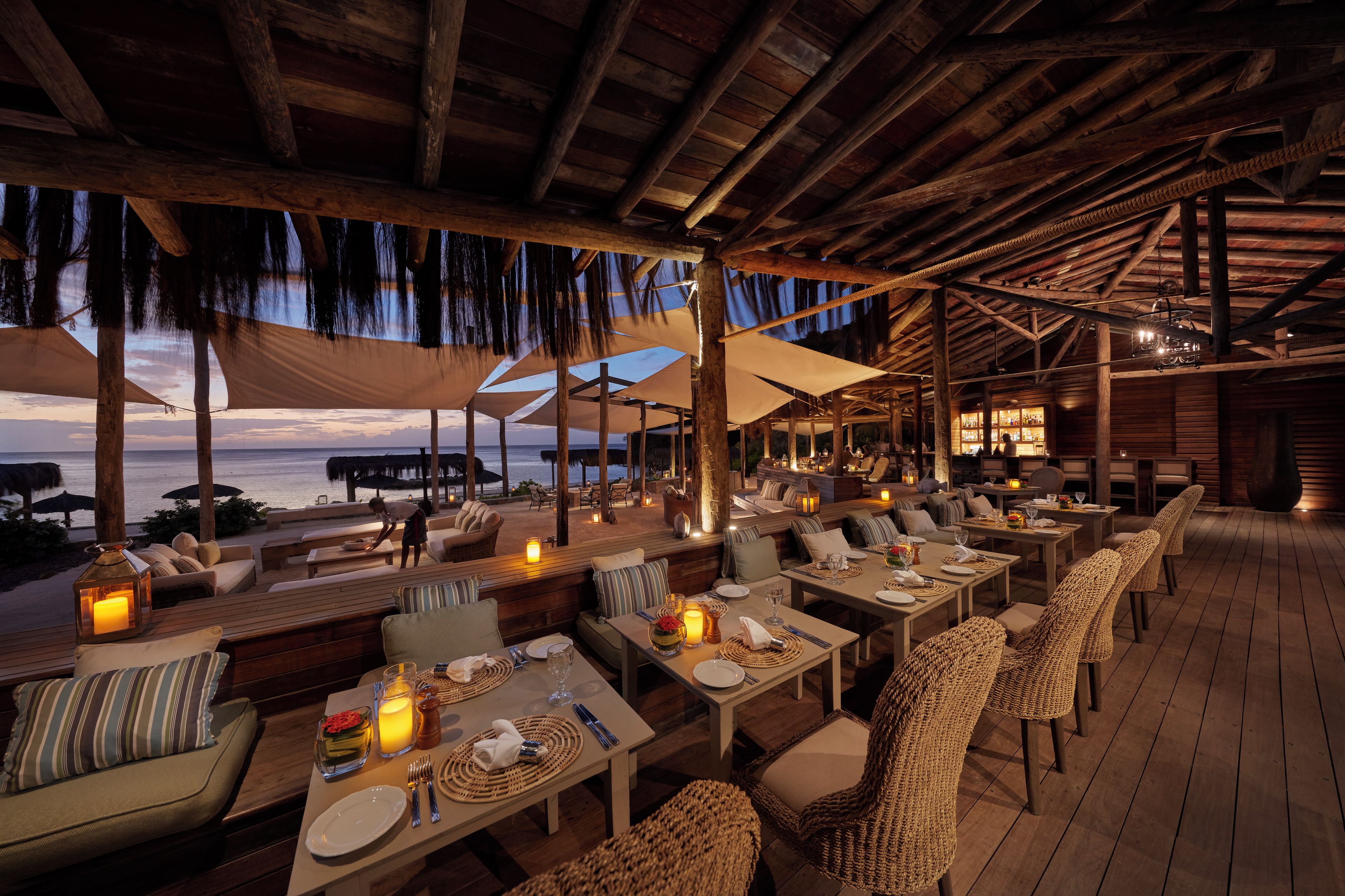 An outdoor dining area with tables and chairs, overlooking the ocean.