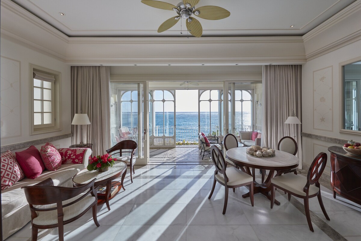 Un comedor amplio con vistas al mar, un ventilador de techo y una mesa con sillas.