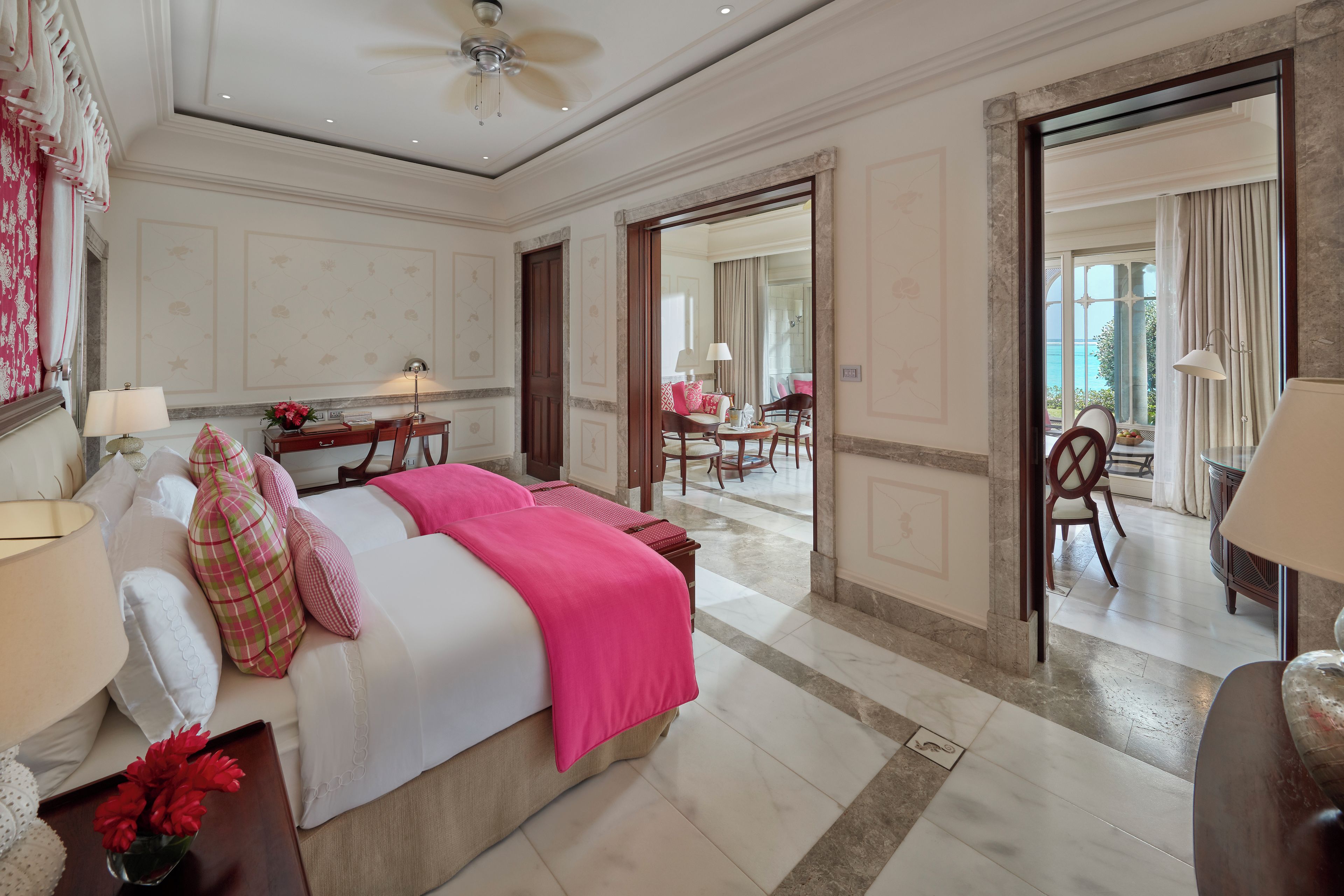 A hotel room with a bed, bedside tables, a desk, and a view of the sea through the window.