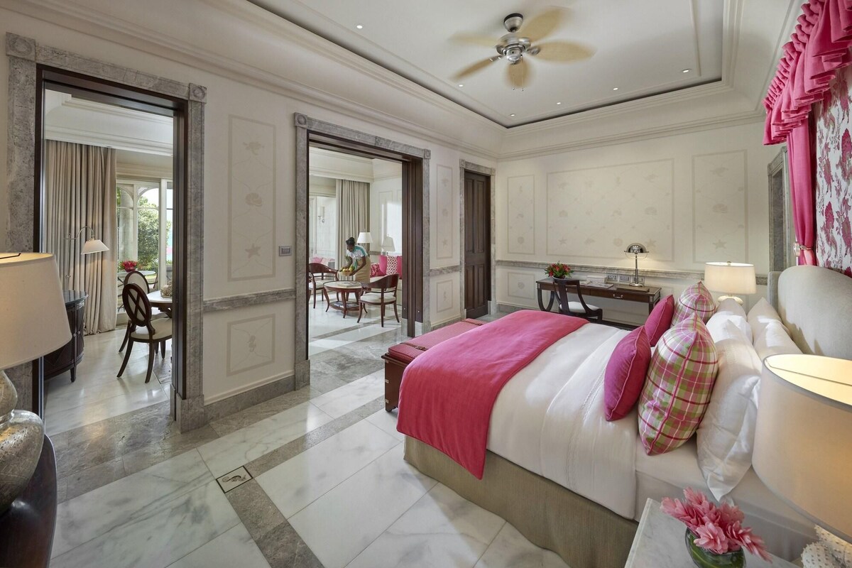 Una habitación de hotel con cama, escritorio, silla y un área de comedor con mesa y sillas.