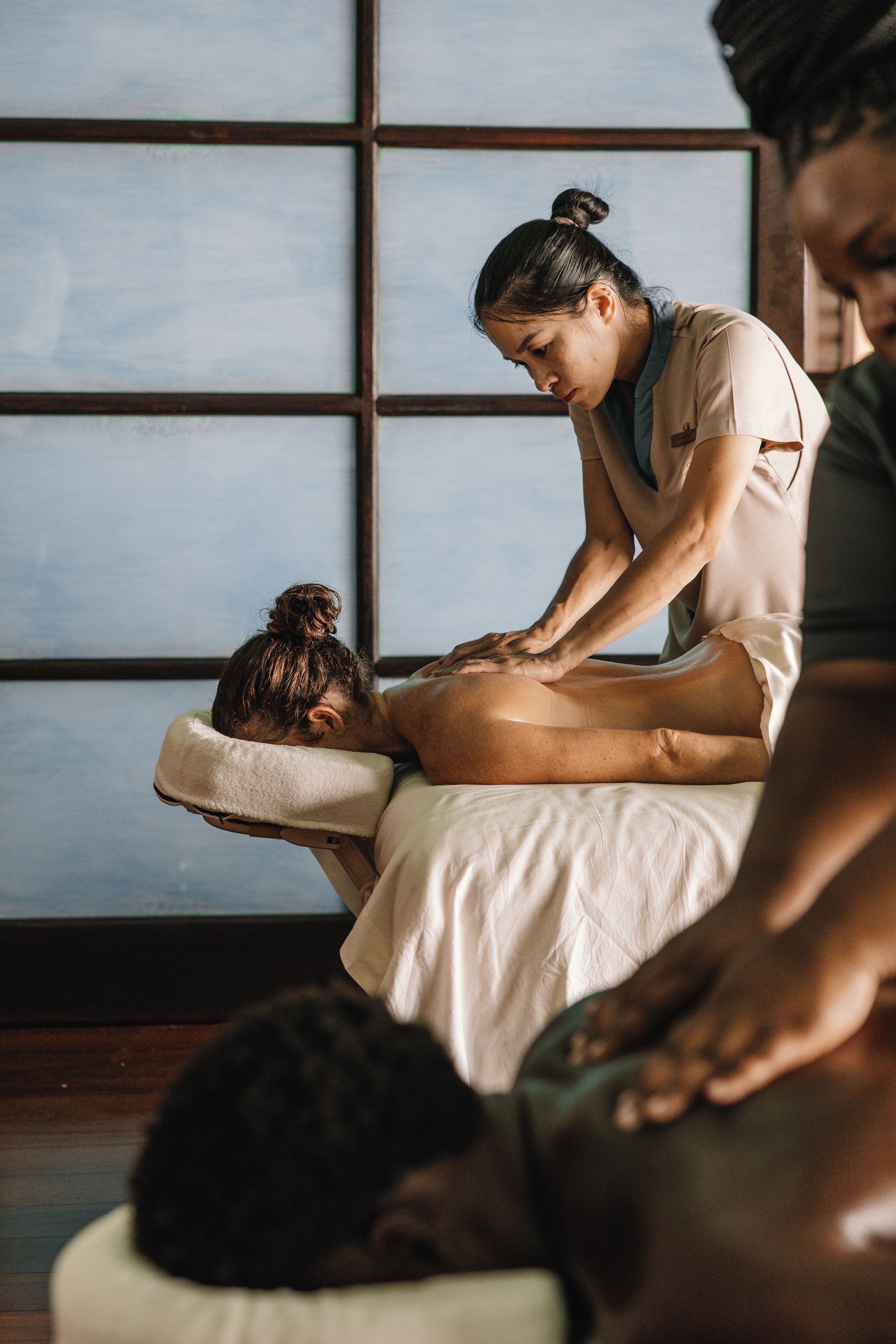 A massage therapy session in a room with a large window and wooden floor.