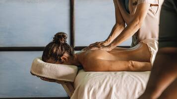 A massage therapy session in a room with a large window and wooden floor.