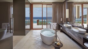 Un baño moderno con una bañera grande, dos lavamanos y vistas al océano.