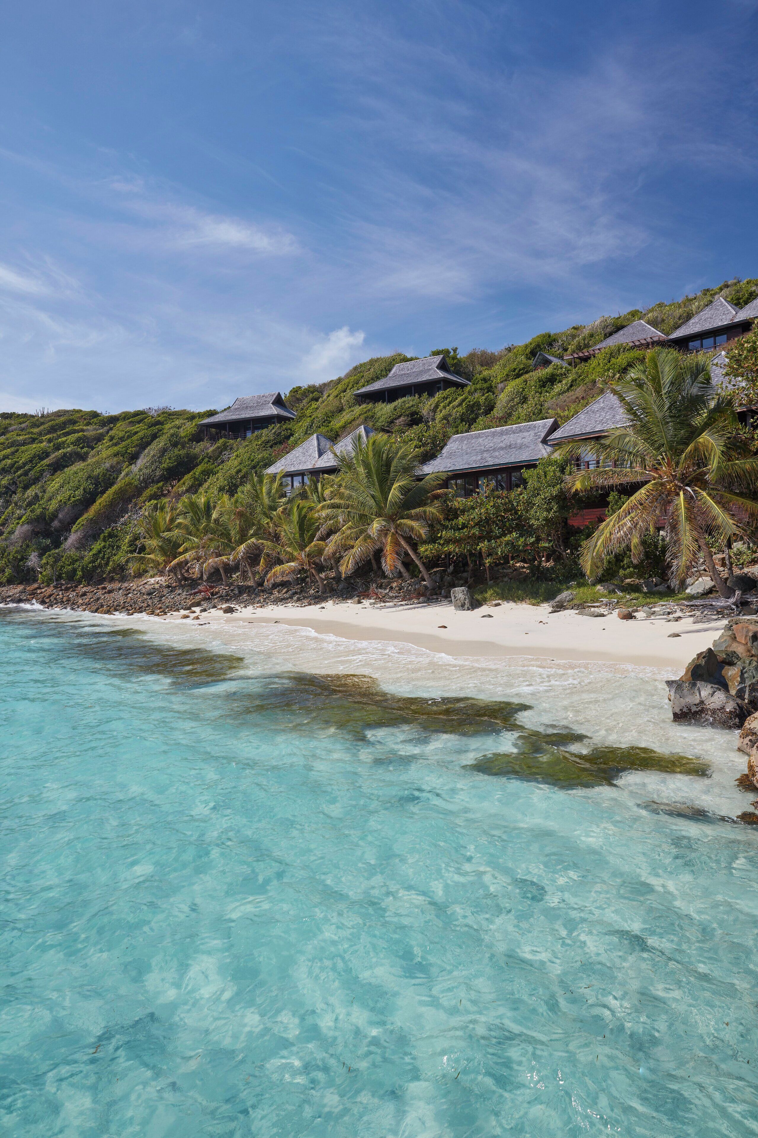 Une propriété située en bord de mer, dotée de plusieurs bungalows sur pilotis, d’eaux turquoise cristallines et d’une végétation luxuriante.