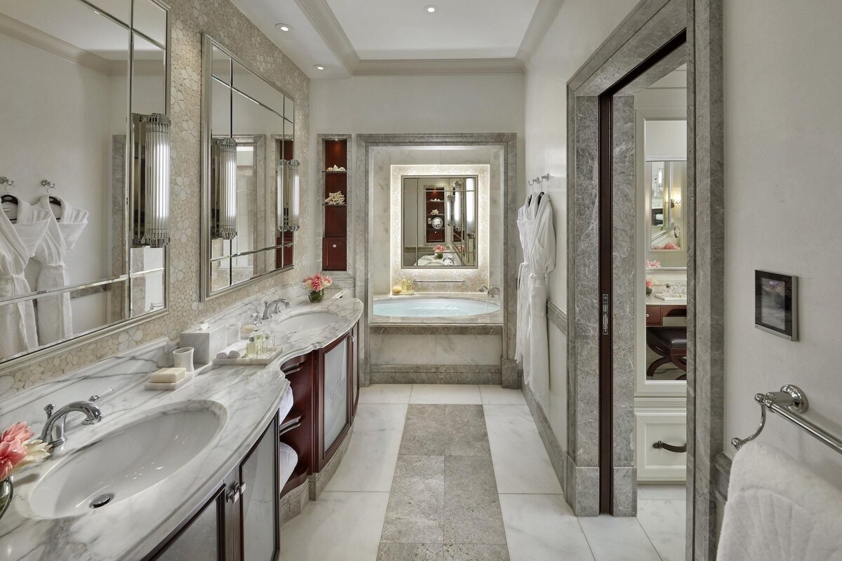 Un baño moderno con un espejo grande, dos lavamanos, una bañera y una ducha a pie.