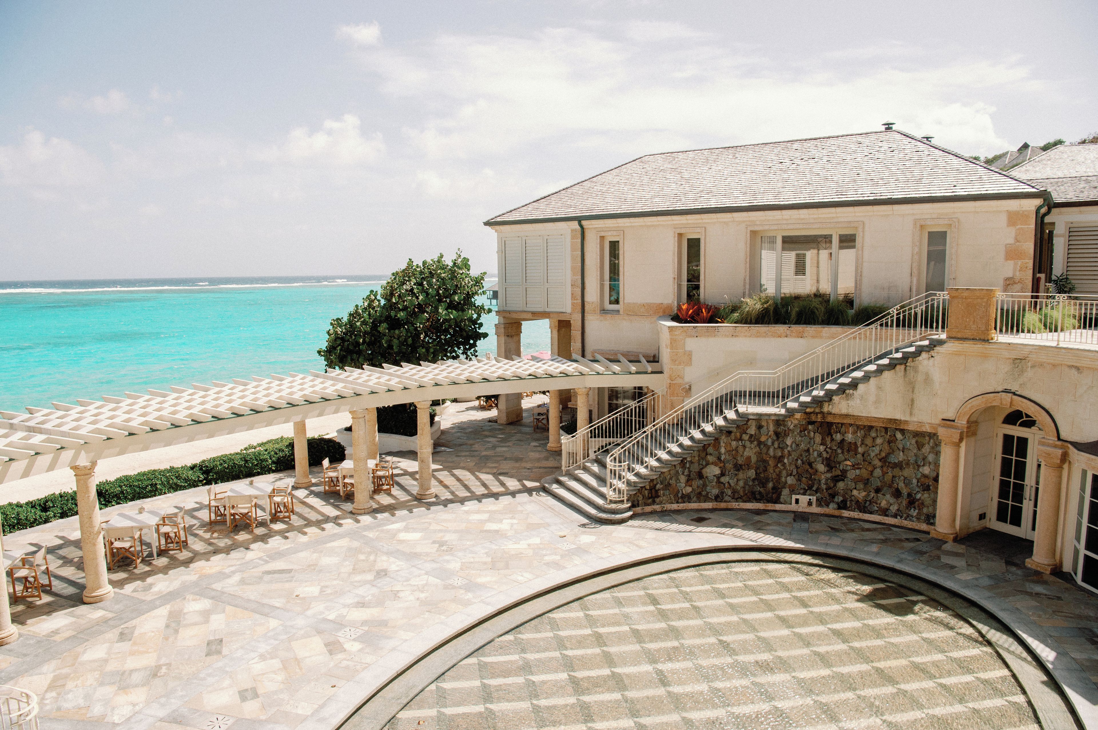 A coastal building with a terrace, outdoor seating, and a view of the sea.