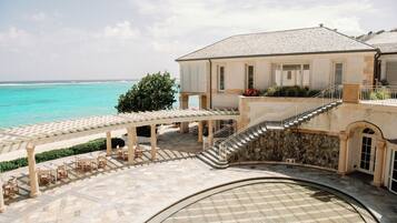 A coastal building with a terrace, outdoor seating, and a view of the sea.
