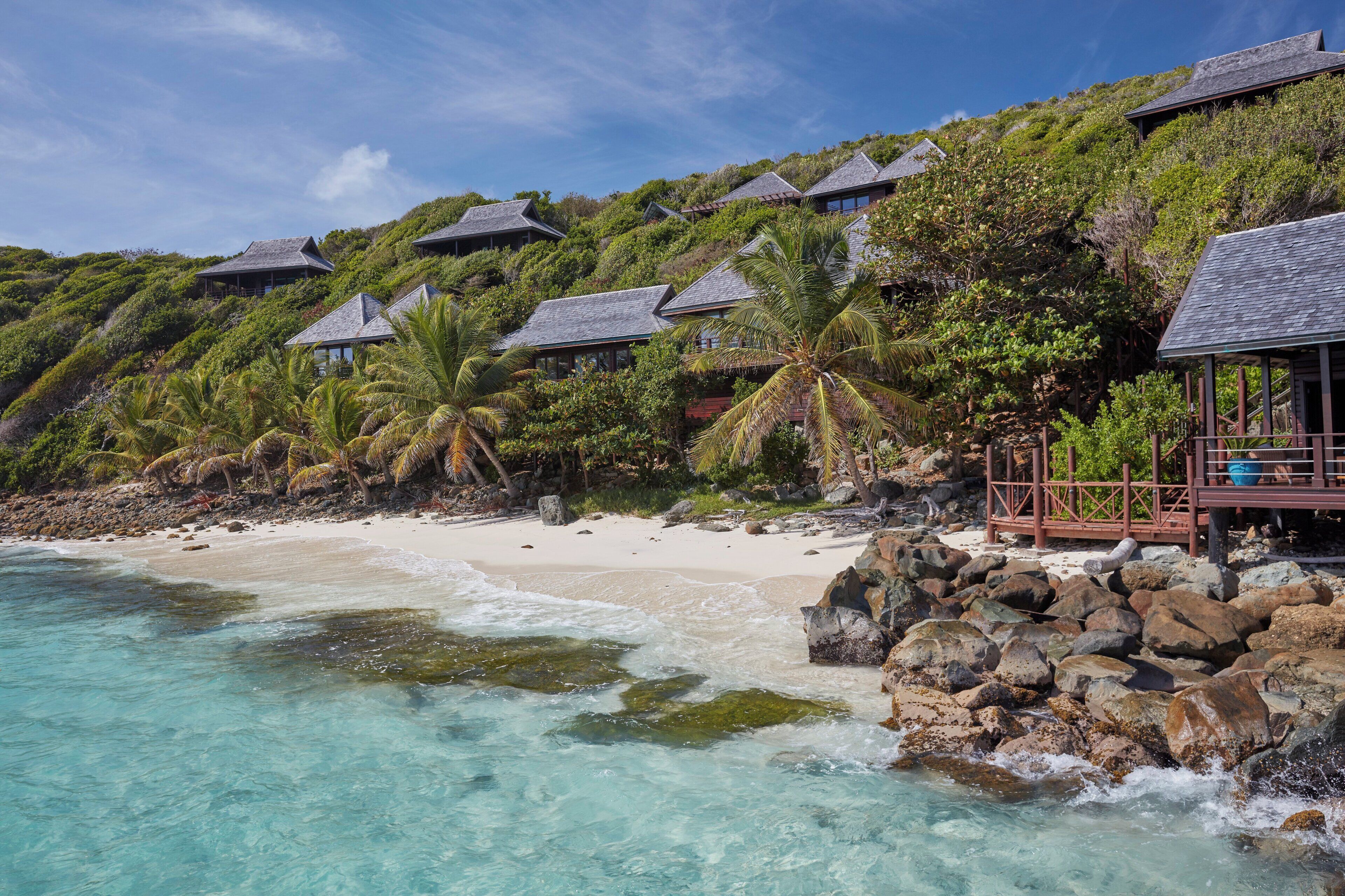 A beachfront property with overwater bungalows, clear turquoise waters, and lush greenery.