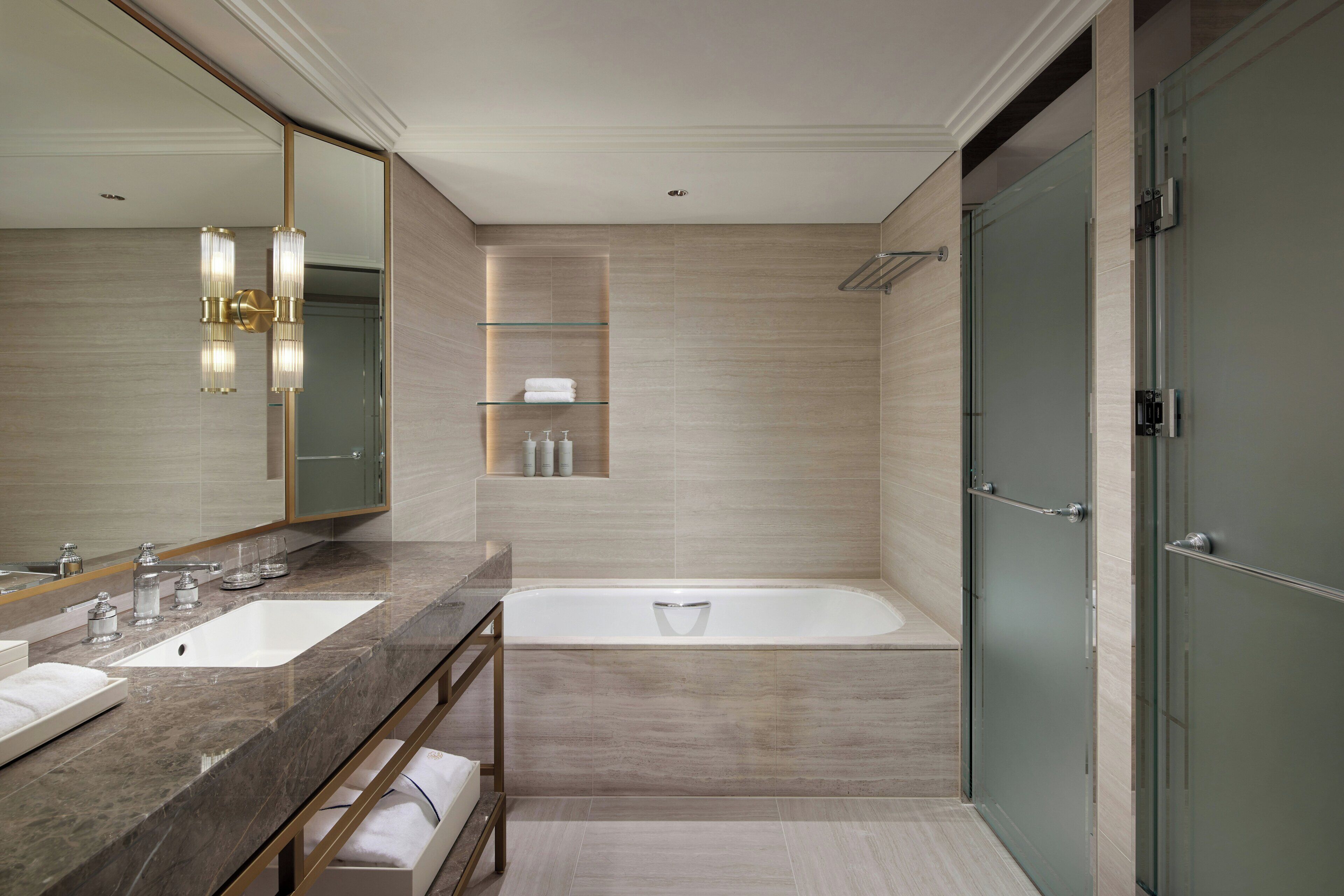 Un baño moderno con dos lavabos, una bañera y un espejo grande.