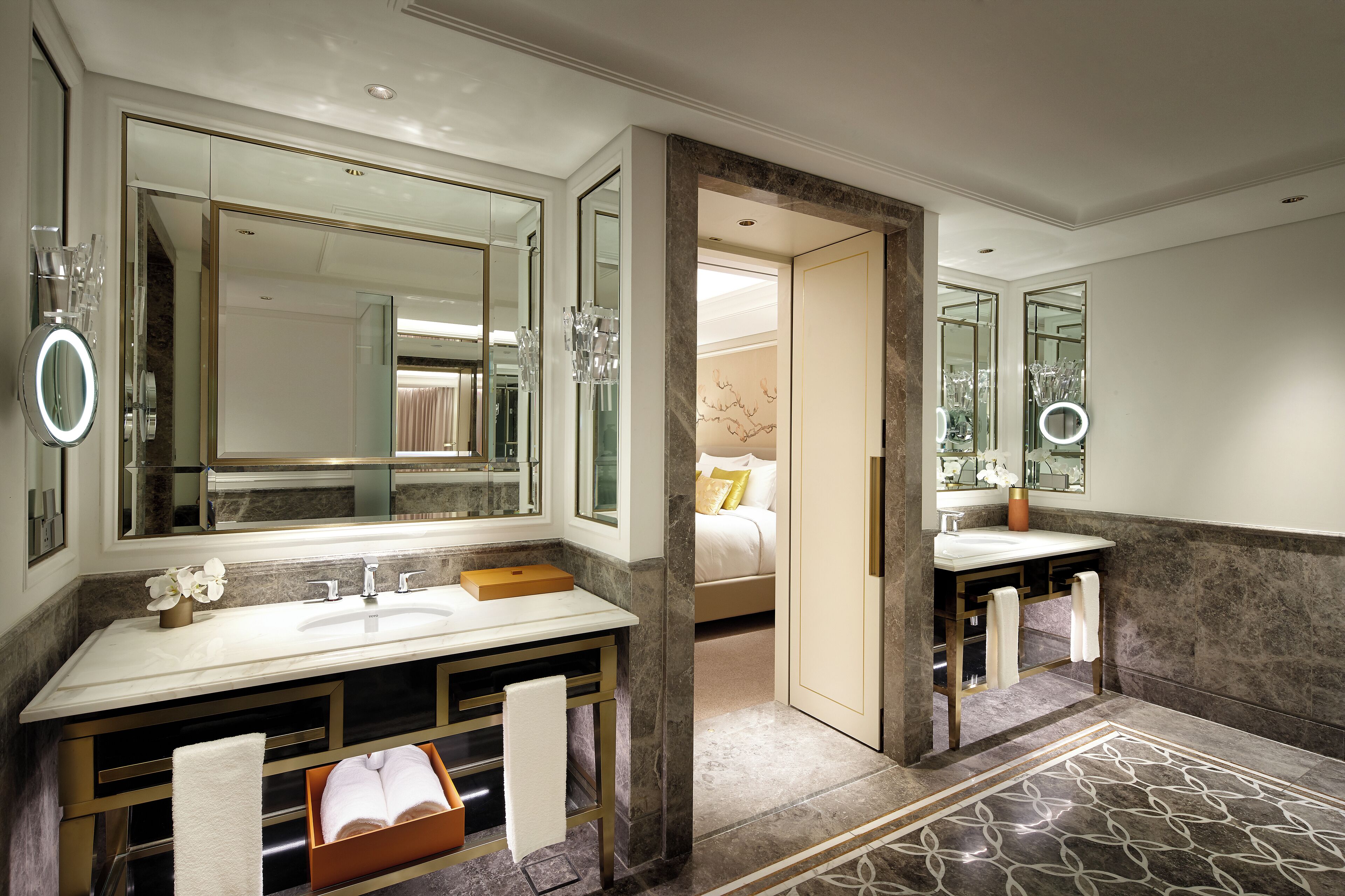A modern bathroom with a large mirror, dual sinks, and a marble floor.