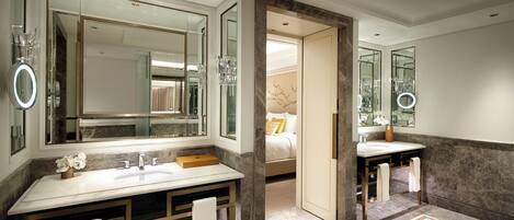 A modern bathroom with a large mirror, dual sinks, and a marble floor.