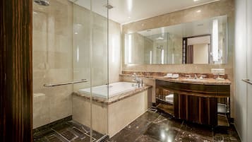 A modern bathroom with a glass-enclosed shower, a marble-tiled floor, and a large mirror above the sink.