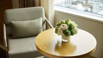 A round wooden table with a vase of flowers in a glass container.