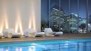 A poolside area with modern lounge chairs and a view of illuminated city buildings at night. -  THE GRAND LOTTE SEOUL (Formerly: Lotte Hotel Seoul) (Seoul)