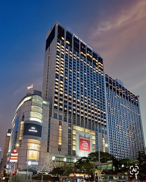 Un hotel moderno de gran altura, con numerosos pisos, amplias ventanas y señalización iluminada.