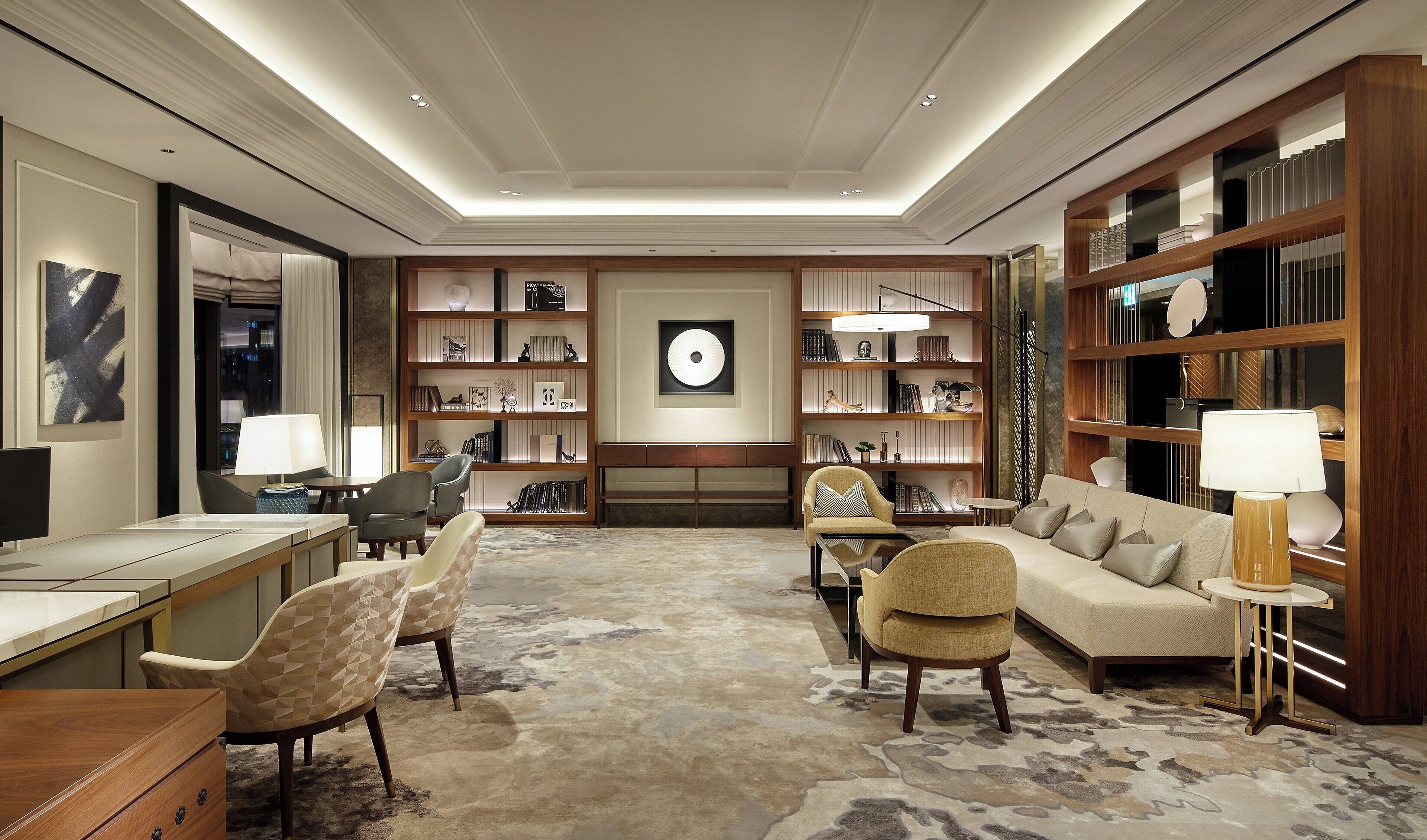 A spacious living room with a large bookshelf, a comfortable sofa, and a dining area with a table and chairs.