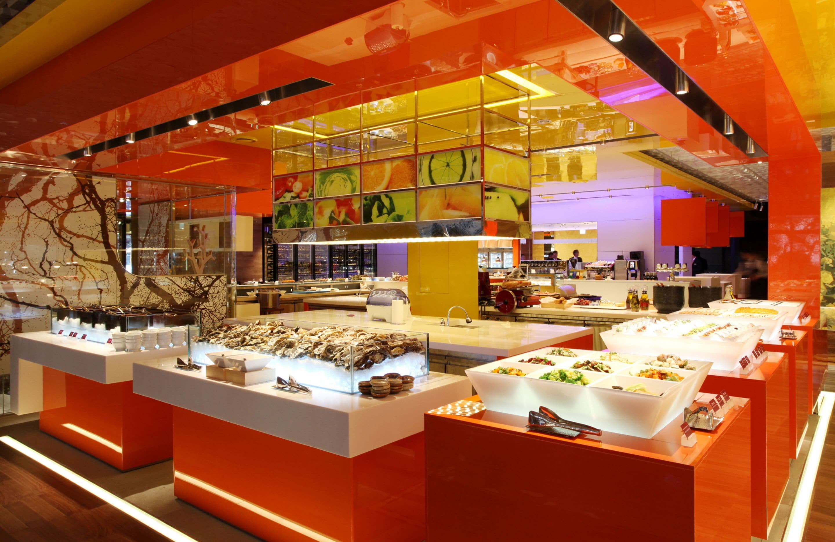 A brightly lit buffet area with multiple food stations and a modern, colorful interior design.