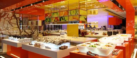 A brightly lit buffet area with multiple food stations and a modern, colorful interior design.