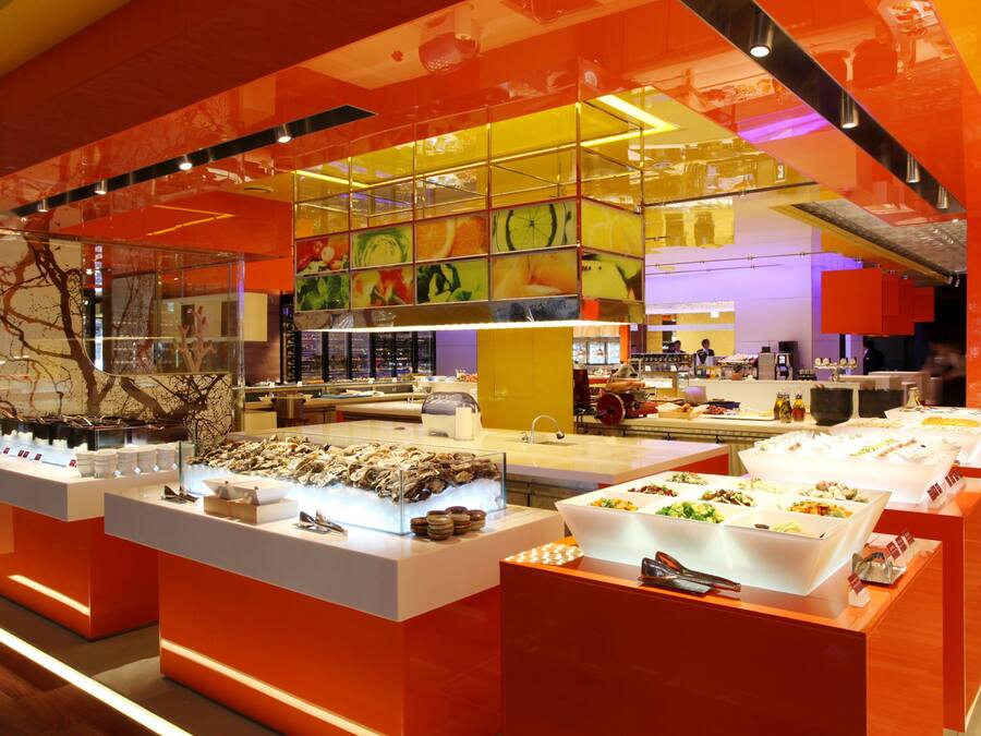 A brightly lit buffet area with multiple food stations and a modern, colorful interior design.