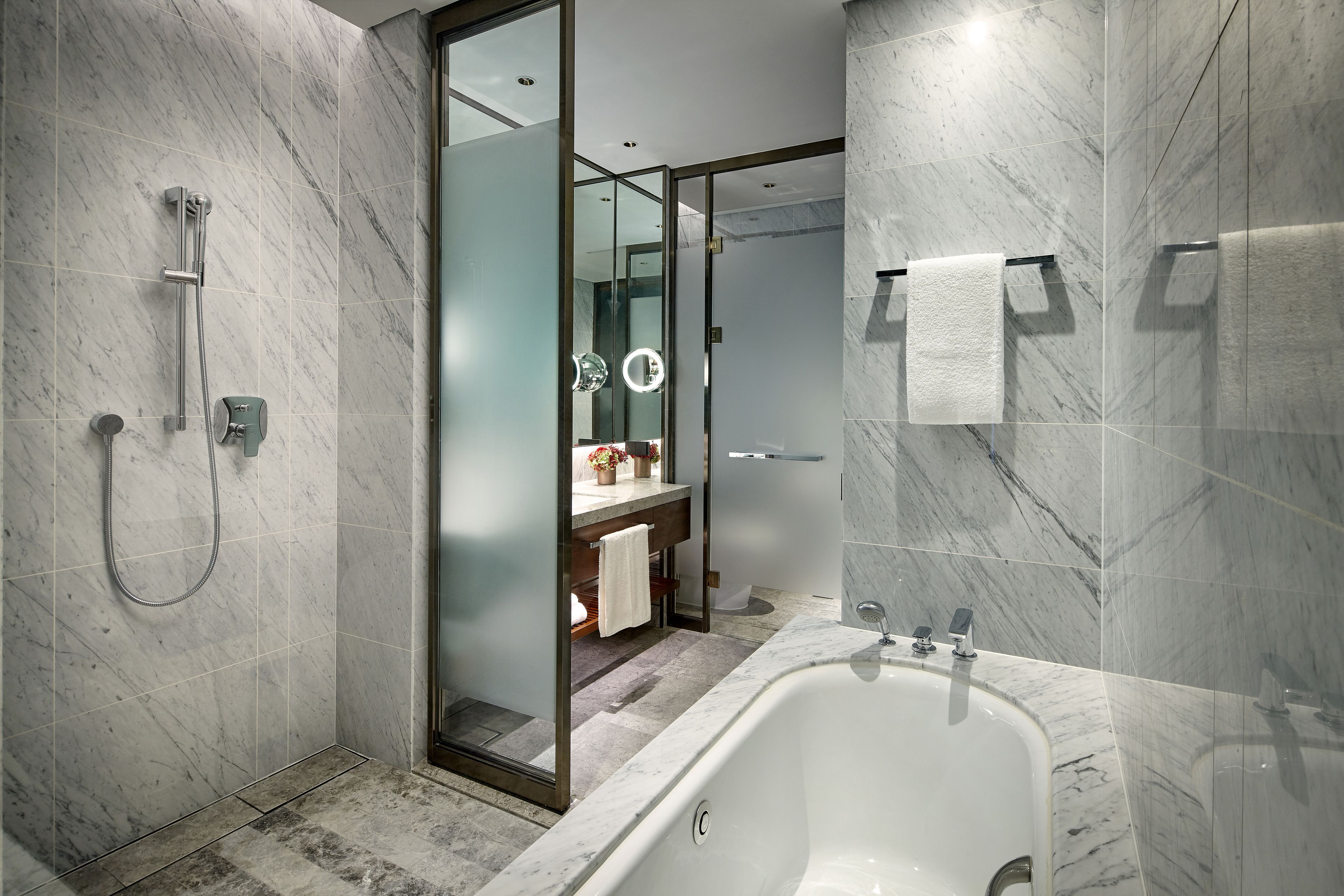 A modern bathroom with a freestanding bathtub, a glass-enclosed shower, and a vanity with a mirror and towel rack.