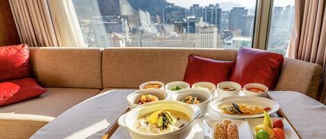 Un montaje para comer sobre un sofá, con una bandeja de comida y una vista urbana de fondo.