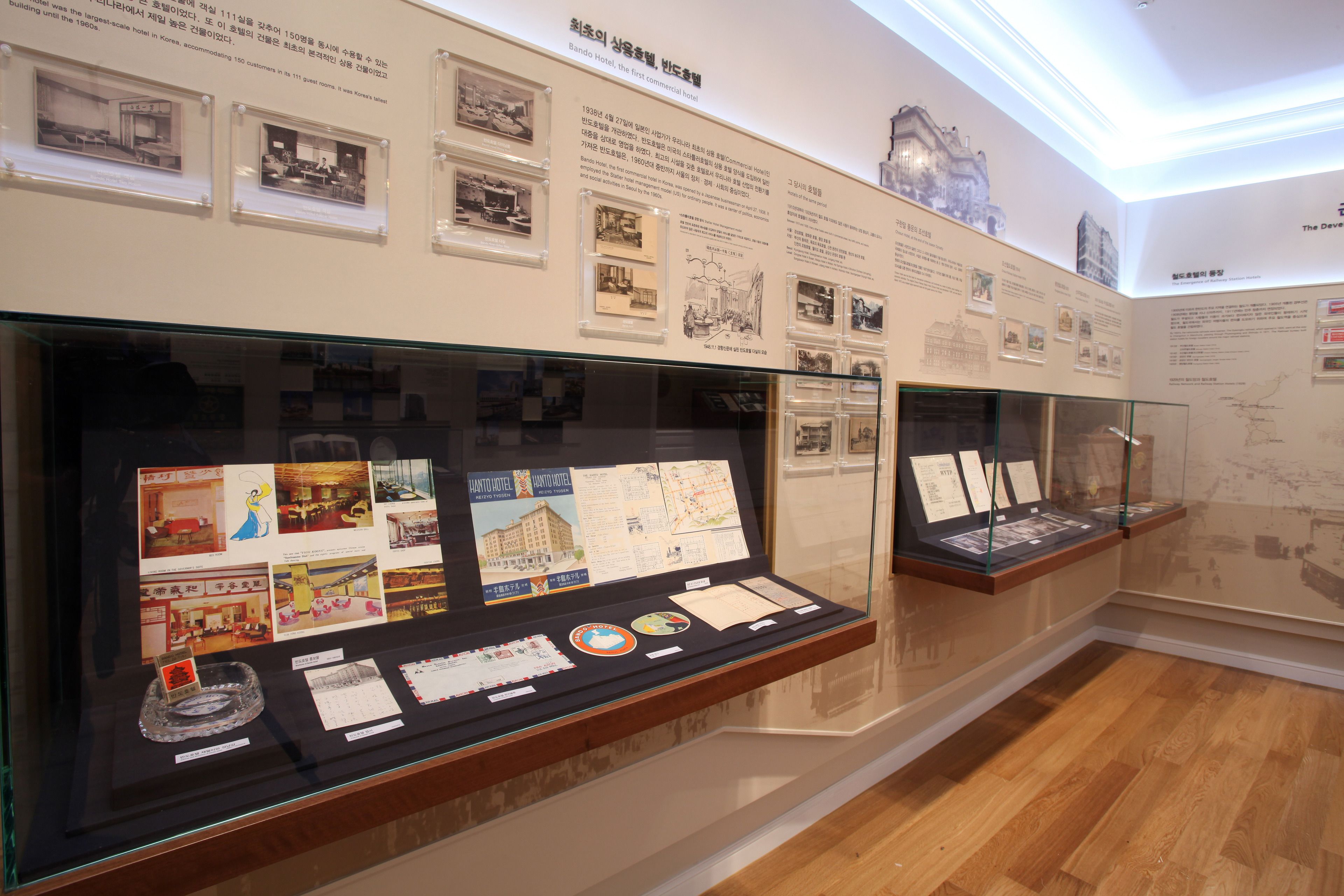 A museum exhibit with historical photographs and documents about the Bando Hotel.