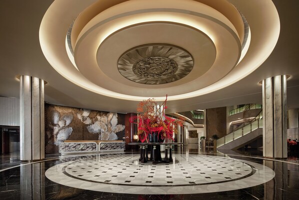 A lobby with a circular central area, a staircase, and a patterned wall.