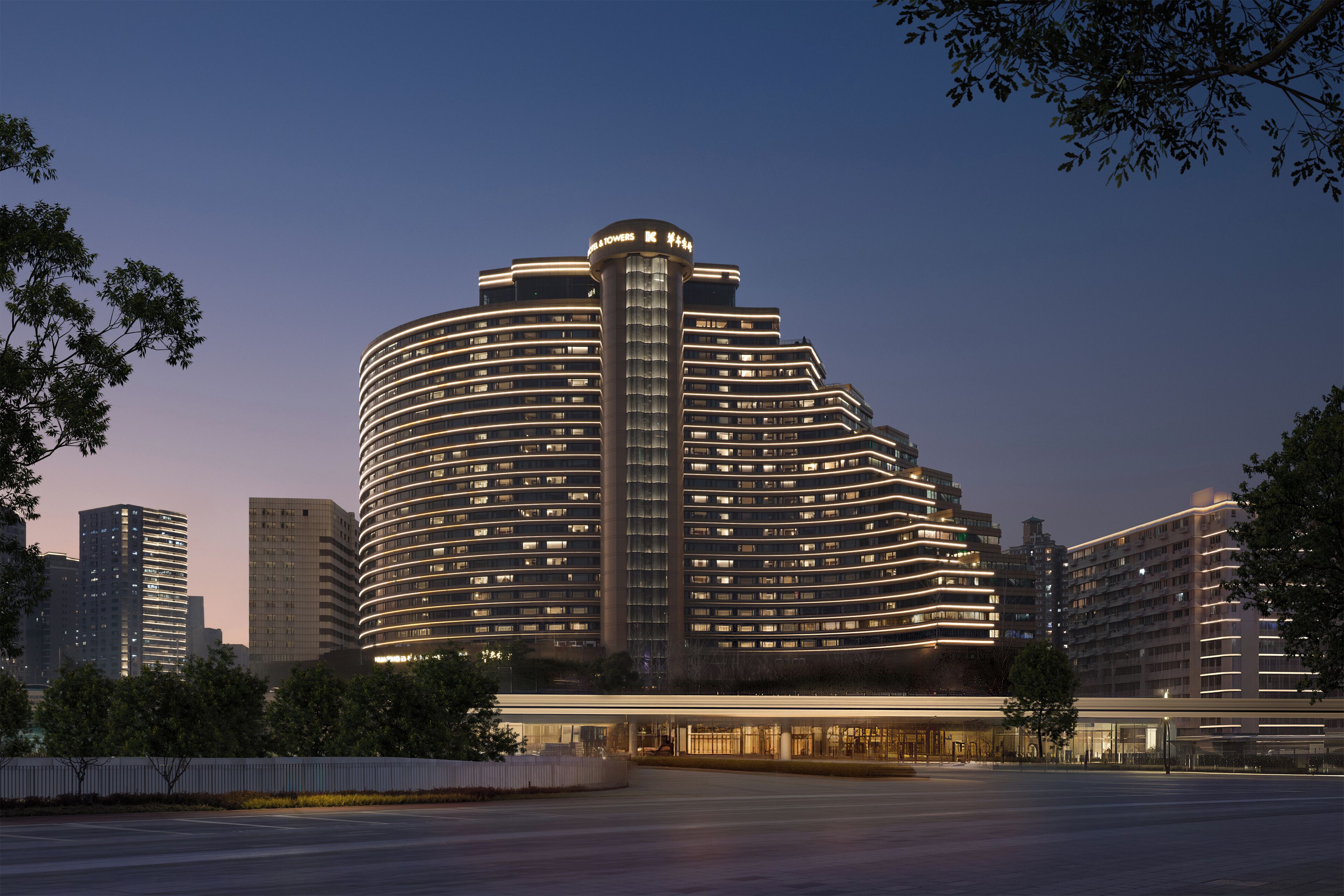 A modern hotel with a curved facade, multiple floors, and illuminated windows.