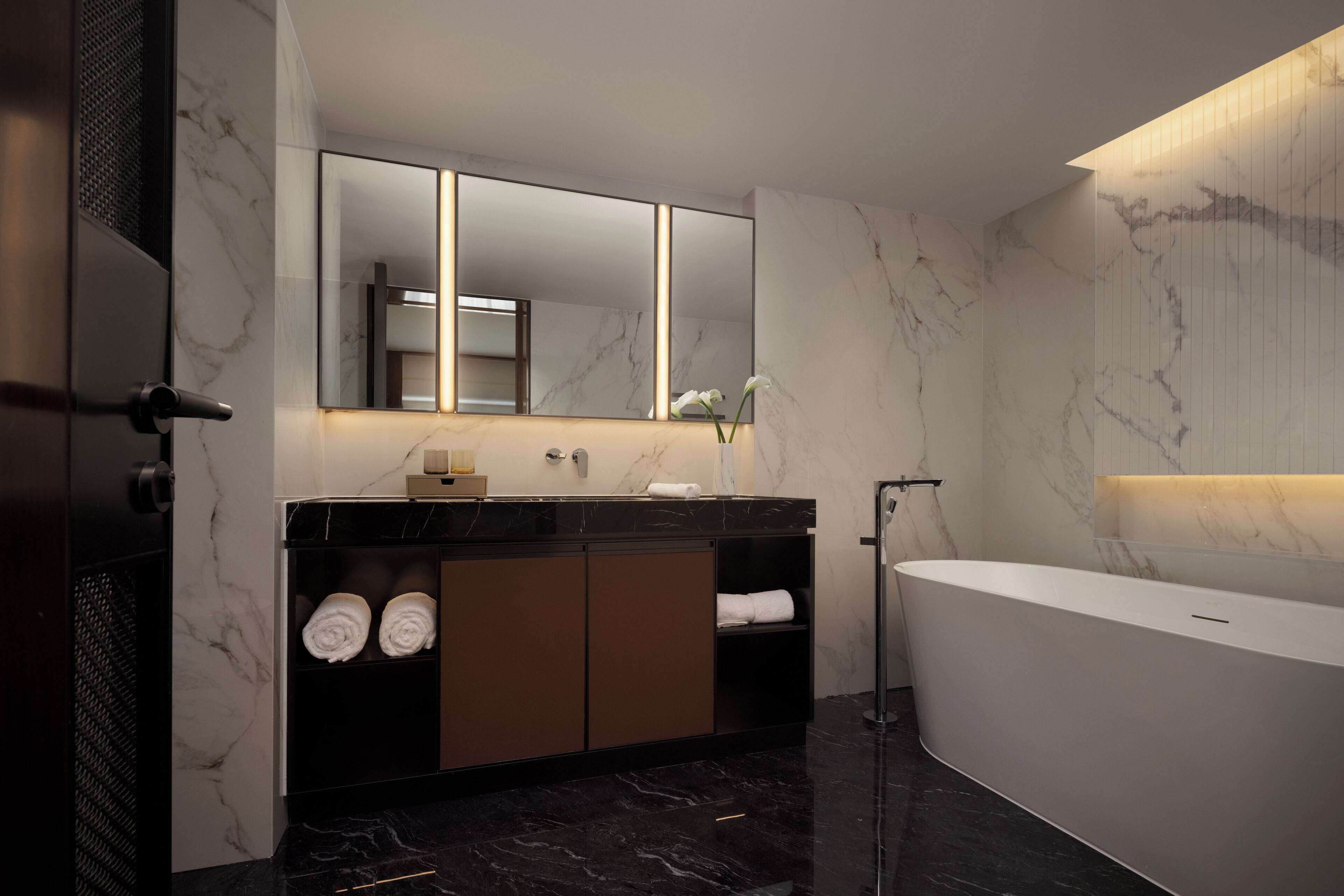 Une salle de bain moderne avec un meuble-lavabo en marbre, un grand miroir, une baignoire et un porte-serviettes.