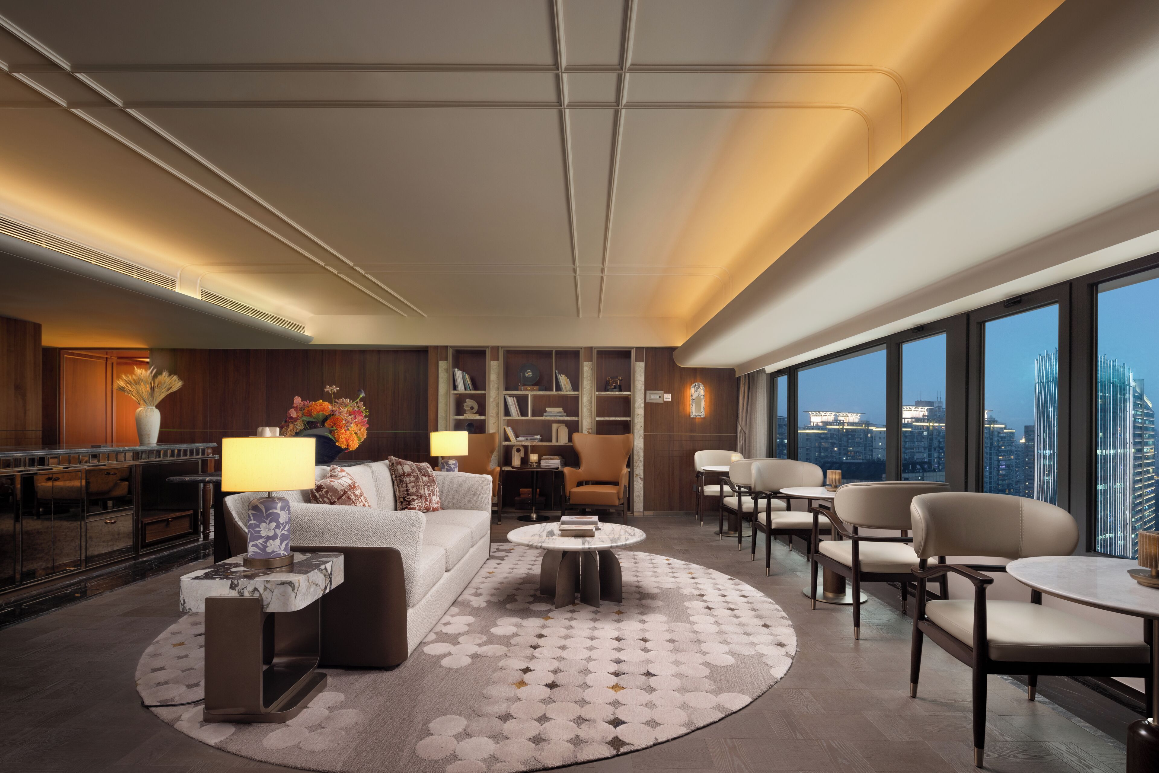 Eine moderne Hotelhalle mit einer Couch, Sesseln, einem Couchtisch und Blick auf die Stadt.