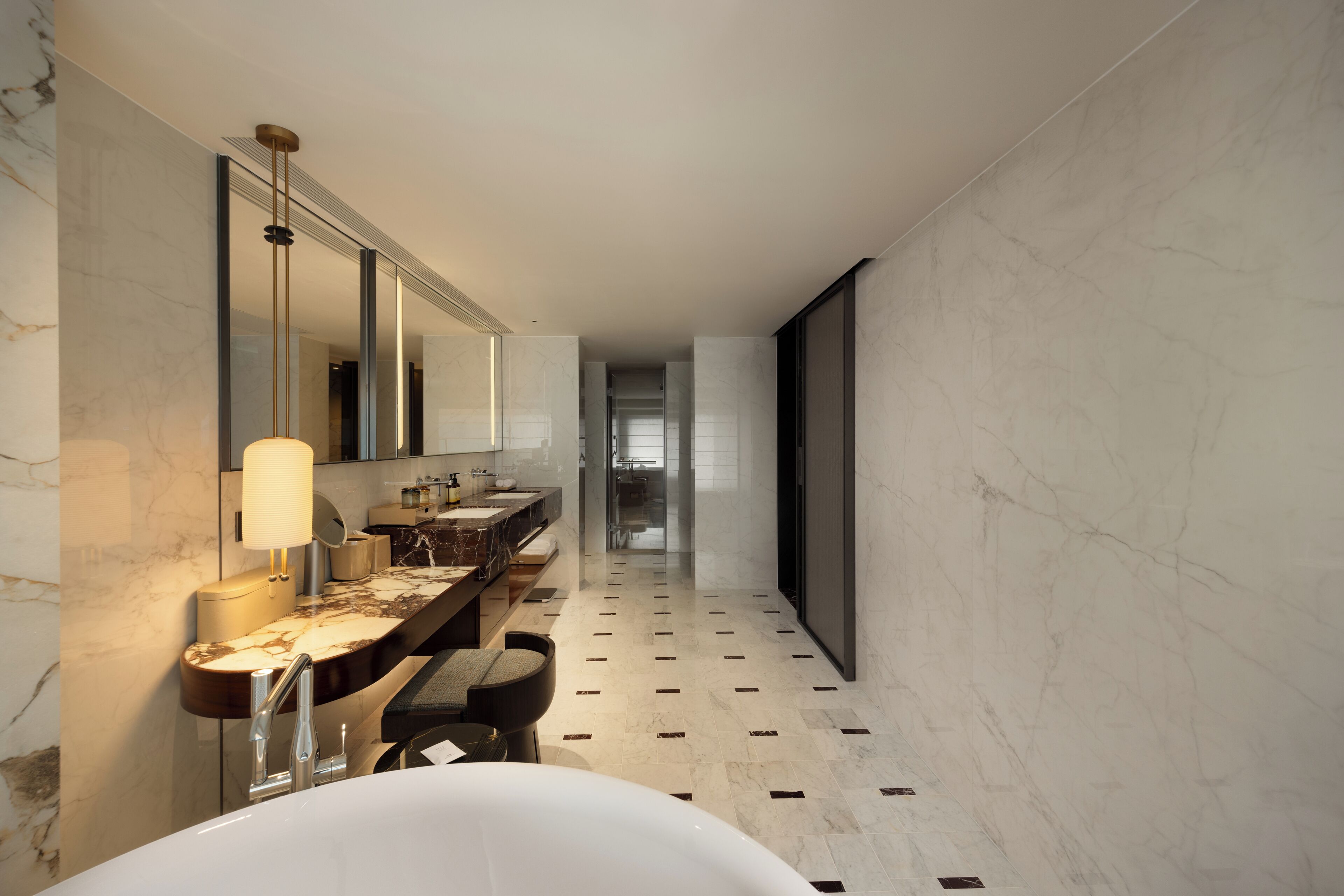 Ein modernes Badezimmer mit einem großen Spiegel, zwei Waschbecken, einer Badewanne und einem gemusterten Boden.