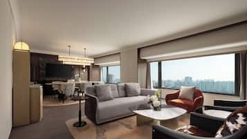 Een moderne woonkamer met een bank, fauteuils, een salontafel, een televisie en uitzicht over de stad.