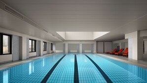 An indoor swimming pool with a skylight, tiled walls, and red lounge chairs. - The Kunlun Hua Ting Hotel & Towers,Shanghai (Shanghai)
