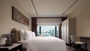 A modern hotel room with a large bed, a desk, a chair, and a city view. - The Kunlun Hua Ting Hotel & Towers,Shanghai (Shanghai)