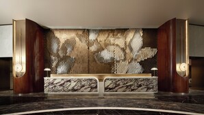 A reception desk with a marble top, a patterned wall, and two wall-mounted lamps. - The Kunlun Hua Ting Hotel & Towers,Shanghai (Shanghai)
