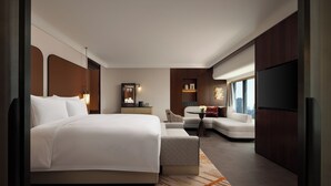 A modern hotel room with a large bed, a sofa, a small table, a TV, and a city view. - The Kunlun Hua Ting Hotel & Towers,Shanghai (Shanghai)