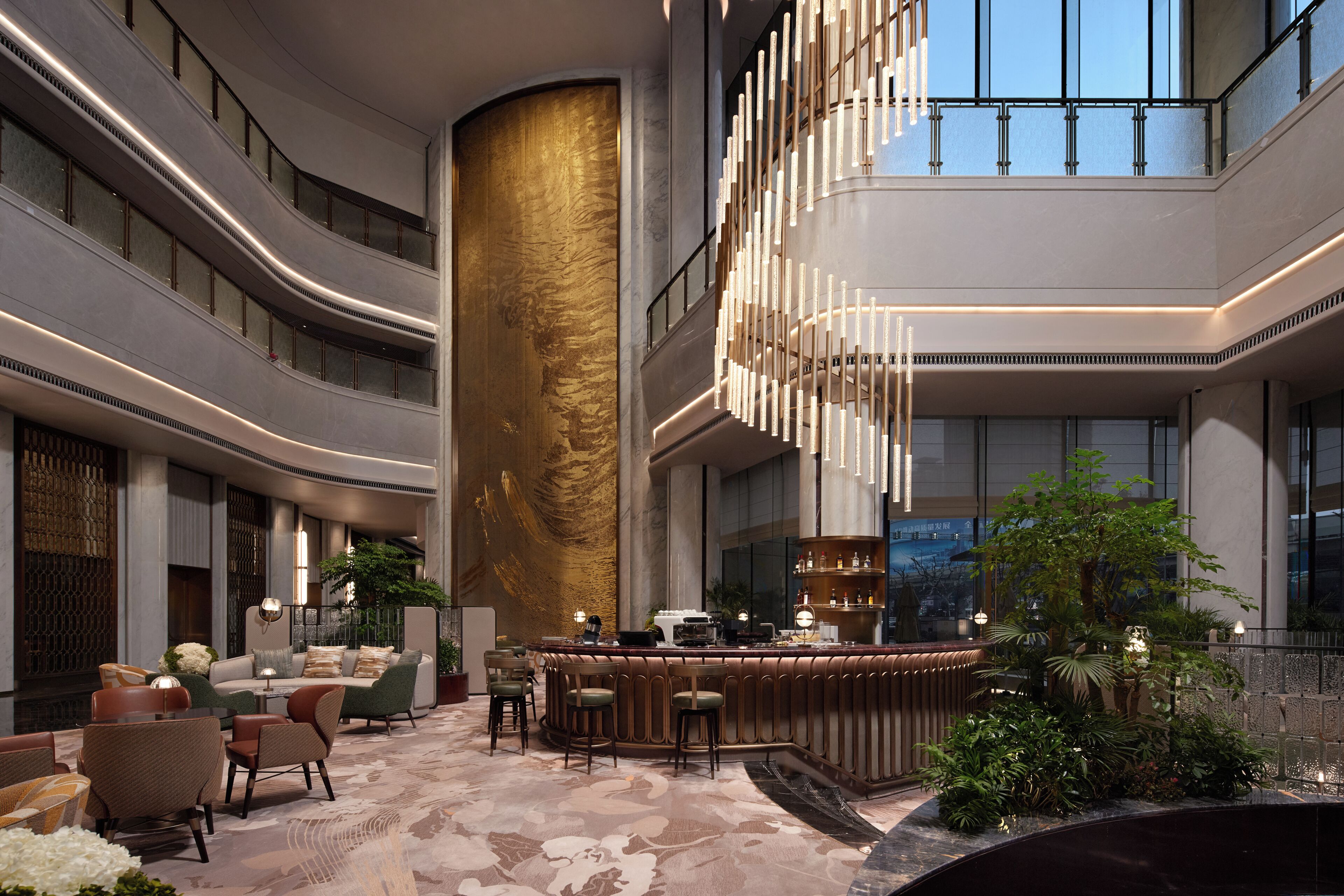 Un moderno vestíbulo de hotel con una zona de asientos curva, una barra central y una columna grande.