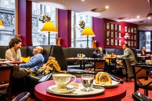 Een knus café met ronde tafels, rode accenten en uitzicht op de stad.