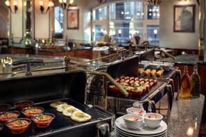 A buffet setup with various food items and a grill station.