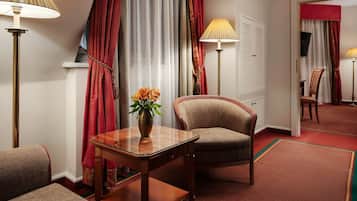 A hotel room with a wooden table, a chair, a vase with flowers, and two standing lamps.