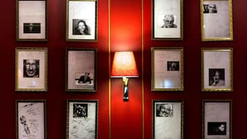 Una pared con fotografías y firmas enmarcadas, iluminada por una lámpara central.