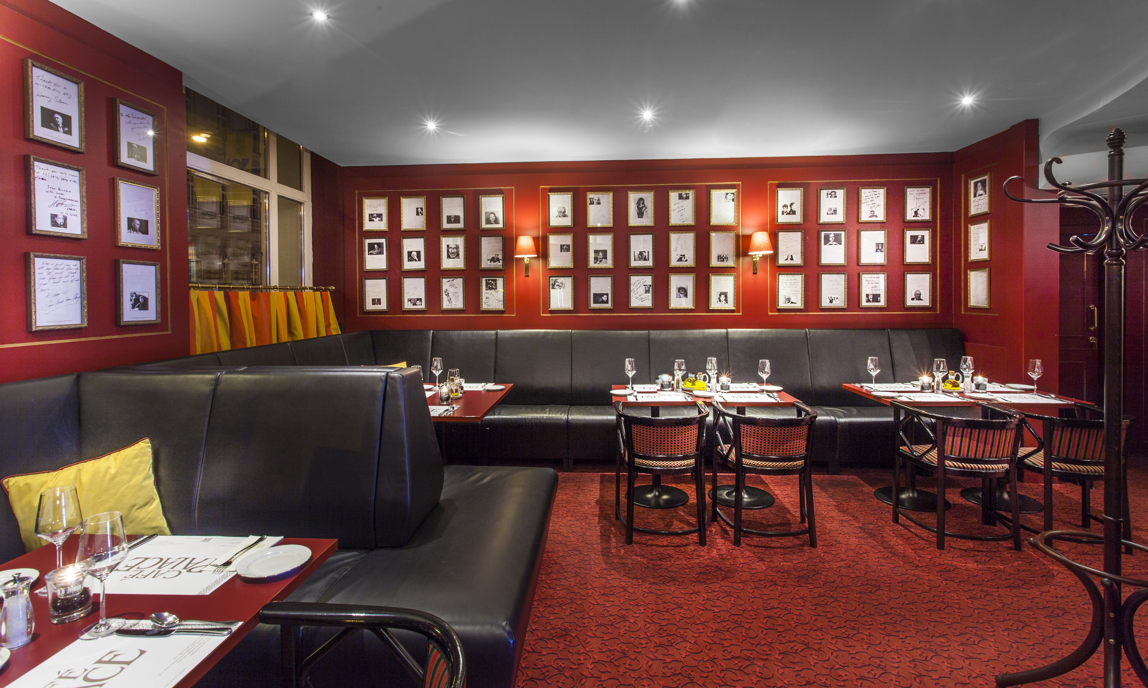 Un restaurante con alfombra roja, asientos de cuero negro y fotografías enmarcadas en las paredes.