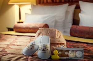 Quarto de hotel com cama, almofadas, abajur, chinelos e um kit de higiene pessoal.