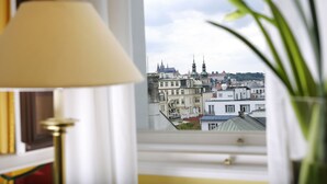 Una habitación con vistas a un paisaje urbano a través de una ventana, que incluye una lámpara y una planta.