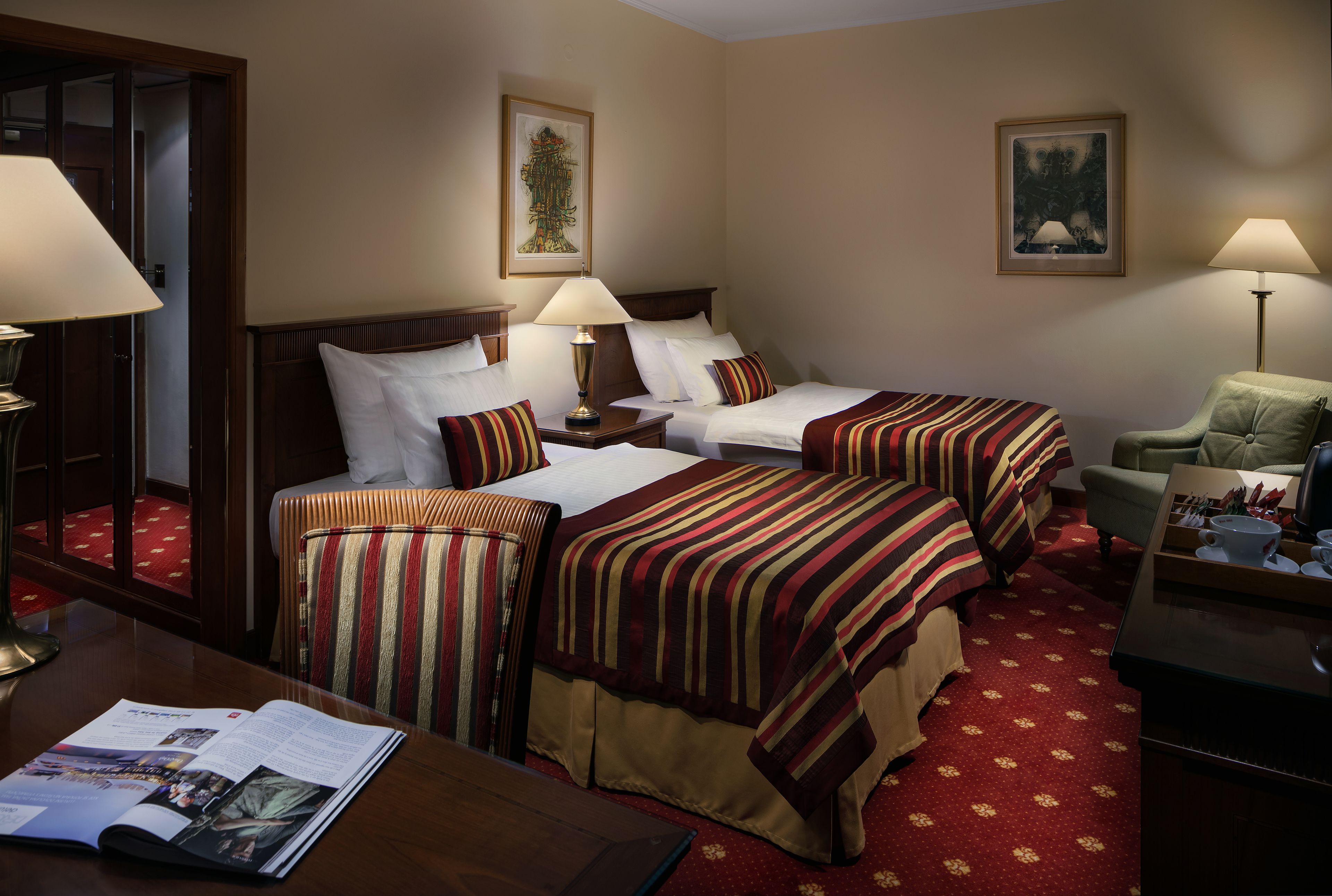 Habitación de hotel con dos camas, un escritorio, una silla y una mesa con una revista.