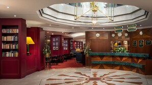 Un vestíbulo de hotel con una recepción, un reloj y una estantería.